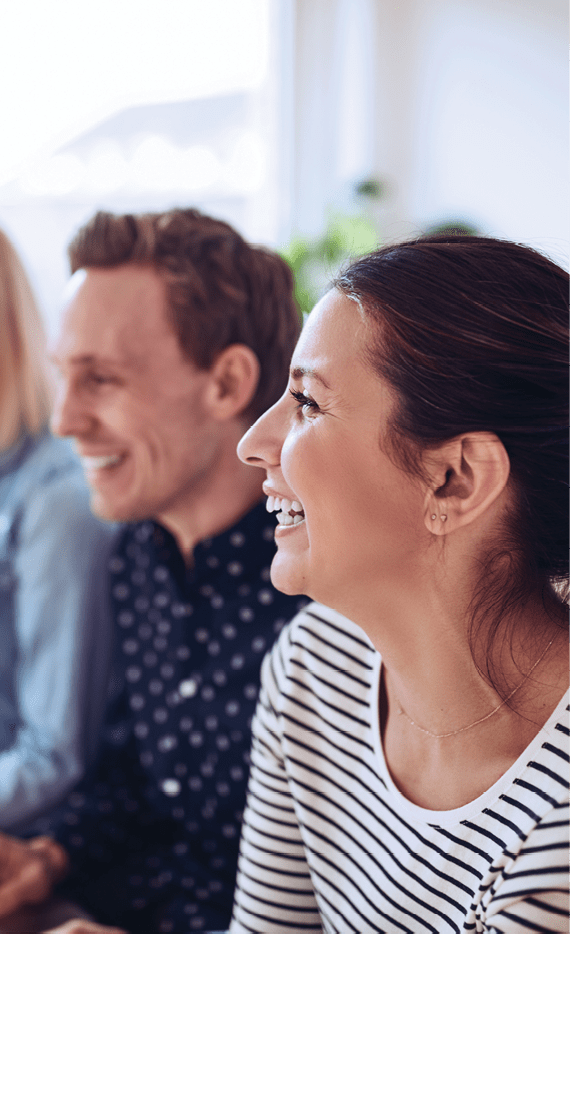 Diverse group of businesspeople laughing while sitting in a row together during a presentation in an office